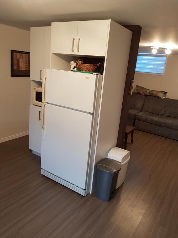 a white refrigerator in a living room with a couch at Gite La Ptite Falaise hébergement touristique in Sainte-Anne-des-Monts