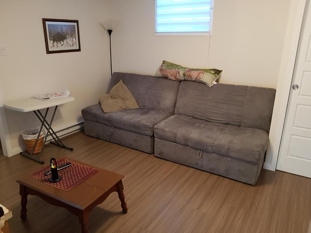 a living room with a couch and a table at Gite La Ptite Falaise hébergement touristique in Sainte-Anne-des-Monts