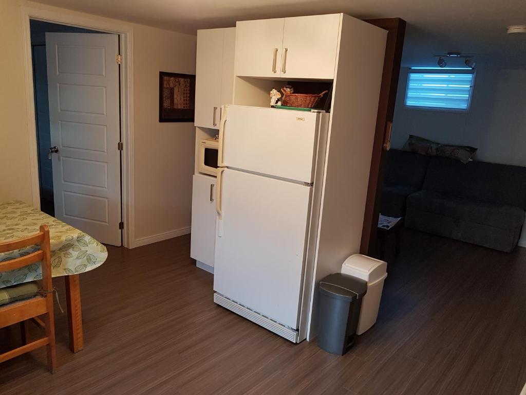 a kitchen with a white refrigerator in a room at Gite La Ptite Falaise hébergement touristique in Sainte-Anne-des-Monts