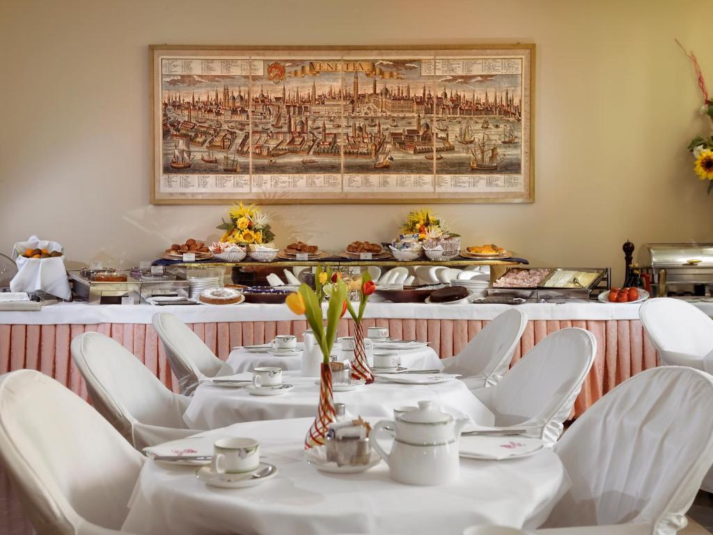 a dining room with white tables and white chairs at Hotel Amadeus in Venice