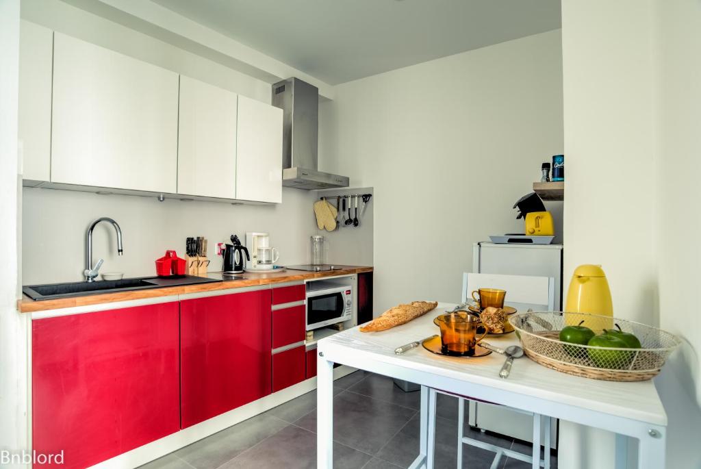 uma cozinha com armários vermelhos e uma mesa com uma taça de fruta em Appartement Place Kléber em Estrasburgo