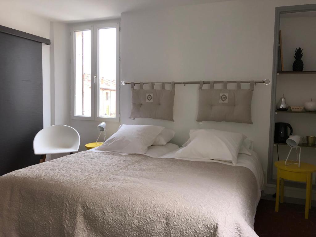 a white bedroom with a large bed with white sheets at La maison de jules in Moustiers-Sainte-Marie