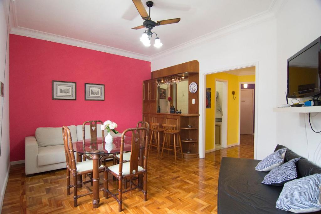 sala de estar con mesa de comedor y pared roja en Flat Imperador, en Petrópolis