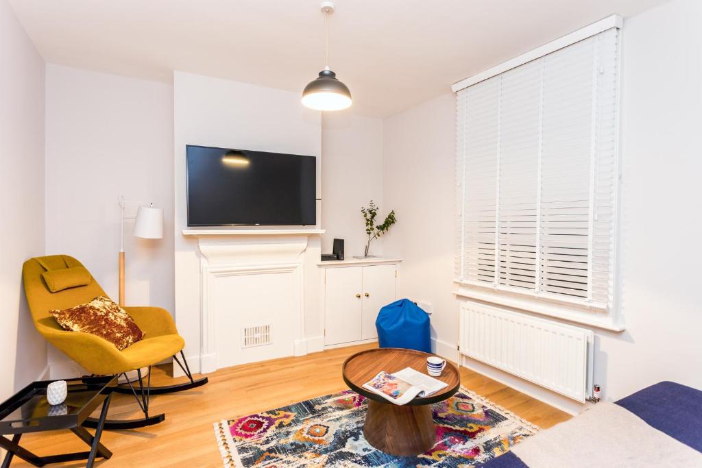 ケンブリッジにあるThe Modern Classic - Contemporary & Elegant 3BDR Homeのリビングルーム(テレビ、黄色い椅子付)