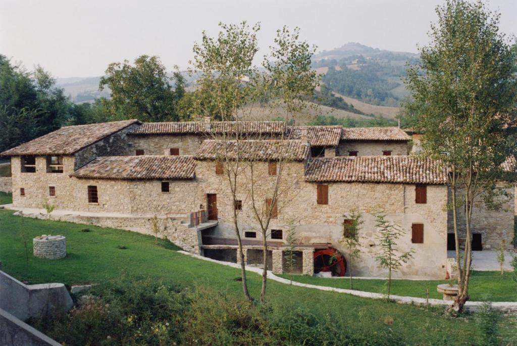 un vieux bâtiment en pierre avec des arbres devant lui dans l'établissement Mulino del Lentino, à Nibbiano