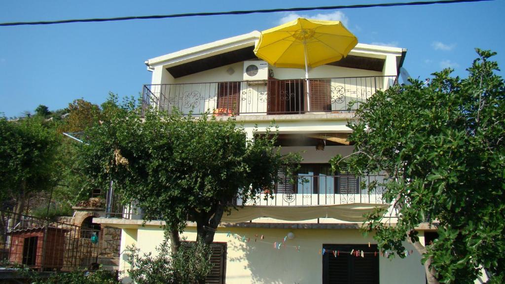 a building with a yellow umbrella on a balcony at Apartments Zuanović in Karlobag