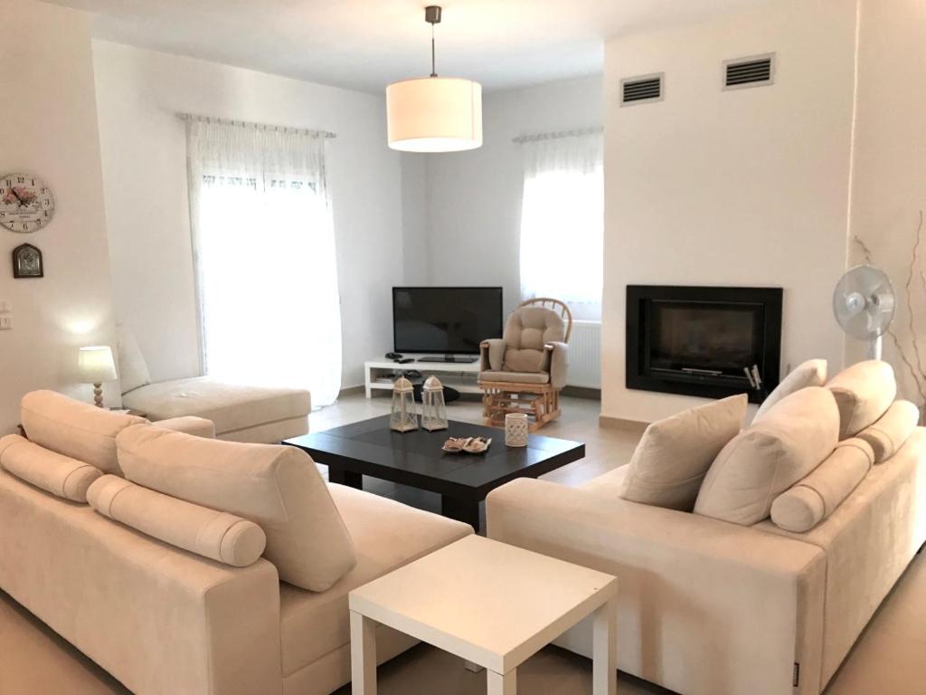 una sala de estar con 2 sofás blancos y una mesa. en Villa Korais Luxury 3br apt with sea view, en Tesalónica