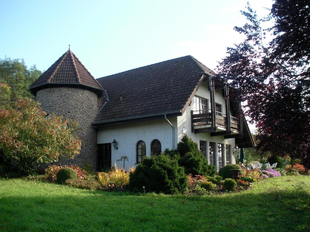 a white house with a turret on a green lawn at Hotel Tannenhof in Gonterskirchen