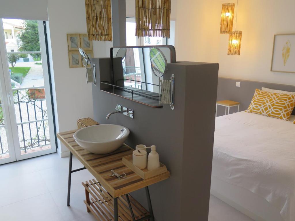 a bathroom with a sink next to a bed at T4 Grand Townhouse Old Village in Vilamoura