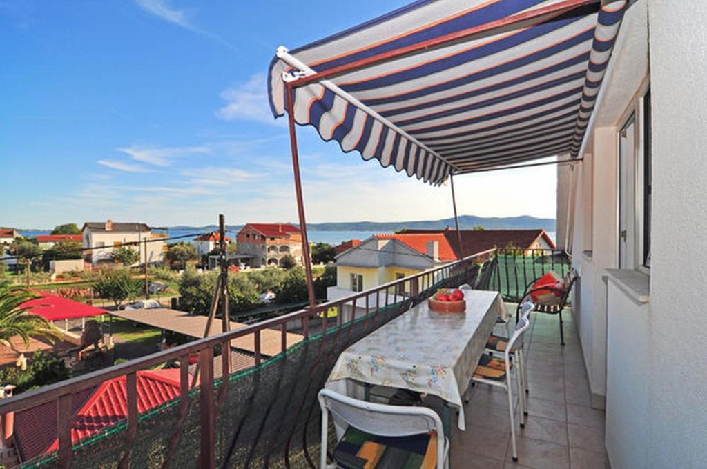 einen Balkon mit einem Tisch, Stühlen und einem Sonnenschirm in der Unterkunft Apartments Jerina in Sukošan
