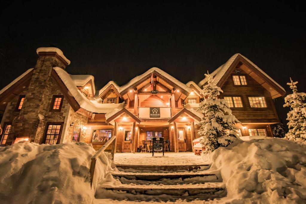 uma casa grande coberta de neve à noite em Winston Lodge em Golden