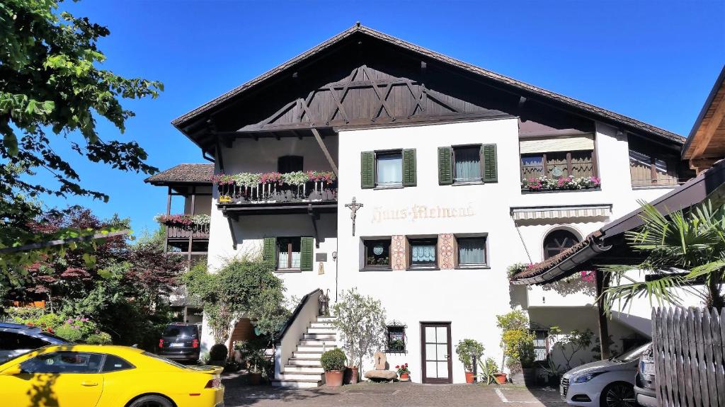 un coche amarillo estacionado frente a un edificio blanco en Garni Meinrad, en Ora - Auer