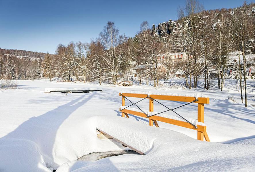 a snow covered field with a wooden fence in it at Hotel Ostrov in Tisá