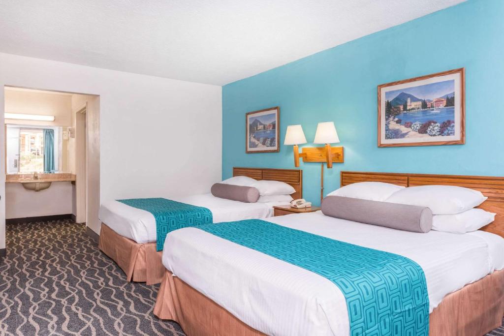 two beds in a hotel room with blue walls at Howard Johnson by Wyndham Commerce GA in Commerce