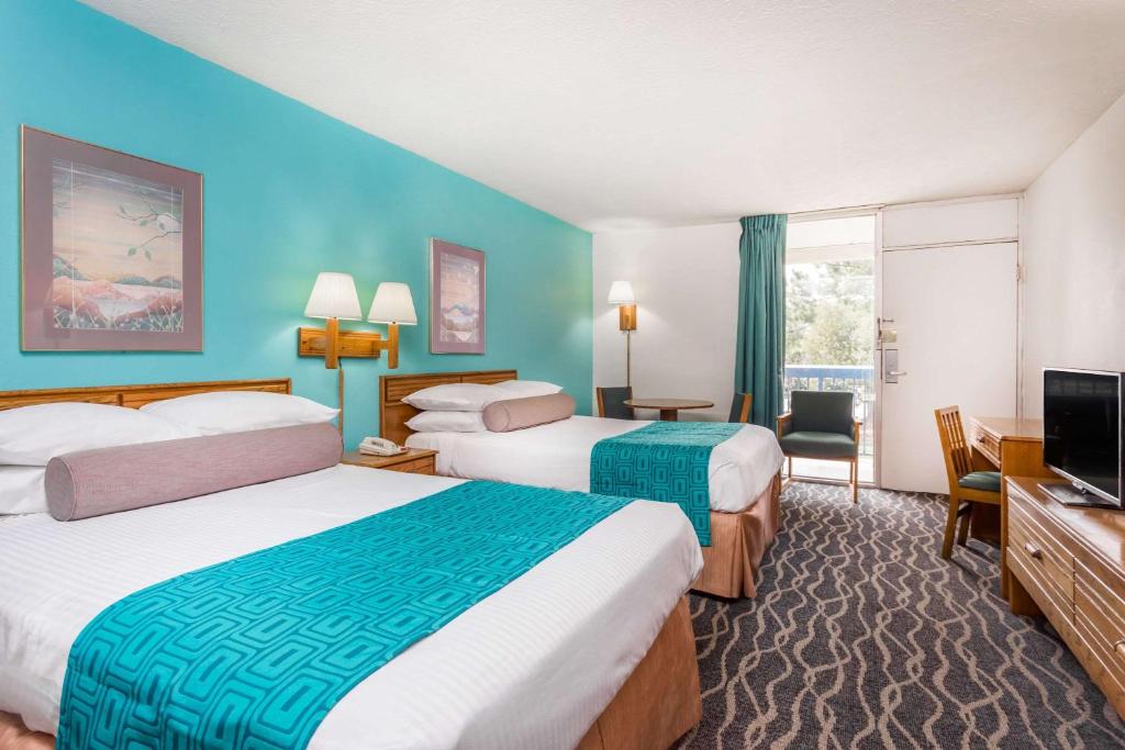 a hotel room with two beds and a flat screen tv at Howard Johnson by Wyndham Commerce GA in Commerce