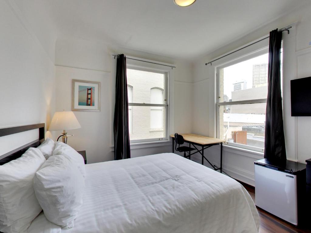 um quarto com uma cama branca, uma secretária e uma janela em Hotel Ikon em São Francisco