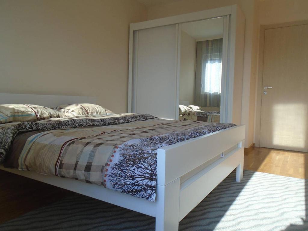 een slaapkamer met een bed en een grote spiegel bij Fantastic brand new apartment in Podgorica