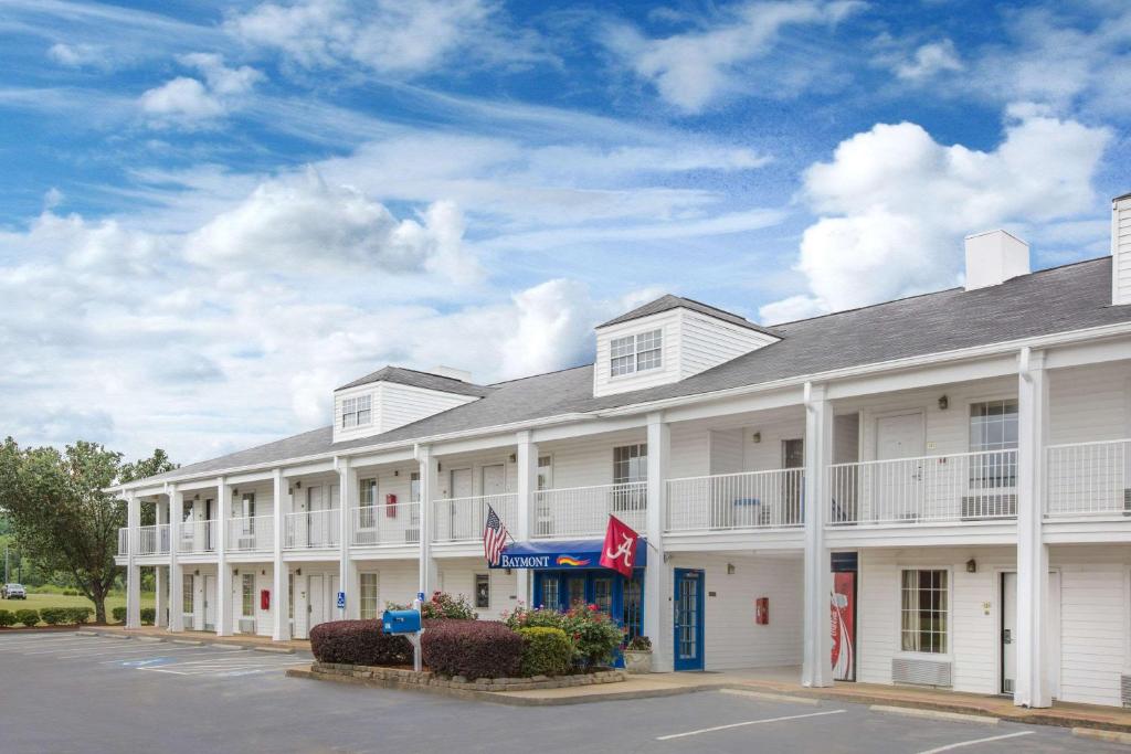 a large white hotel with a parking lot at Baymont by Wyndham Tuscaloosa in Tuscaloosa