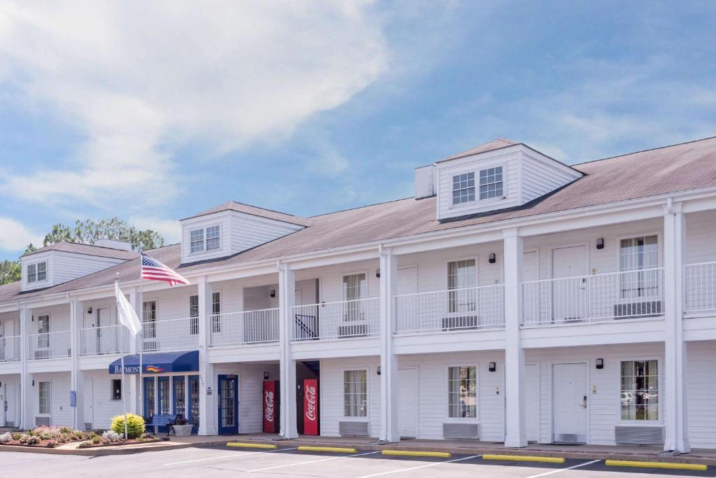 un edificio blanco con una bandera americana delante de él en Baymont by Wyndham Albany at Albany Mall, en Albany