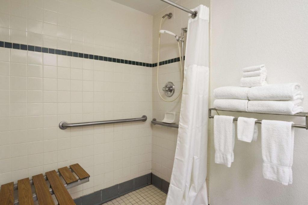 uma casa de banho com um chuveiro e toalhas brancas em Baymont by Wyndham Crossville em Crossville