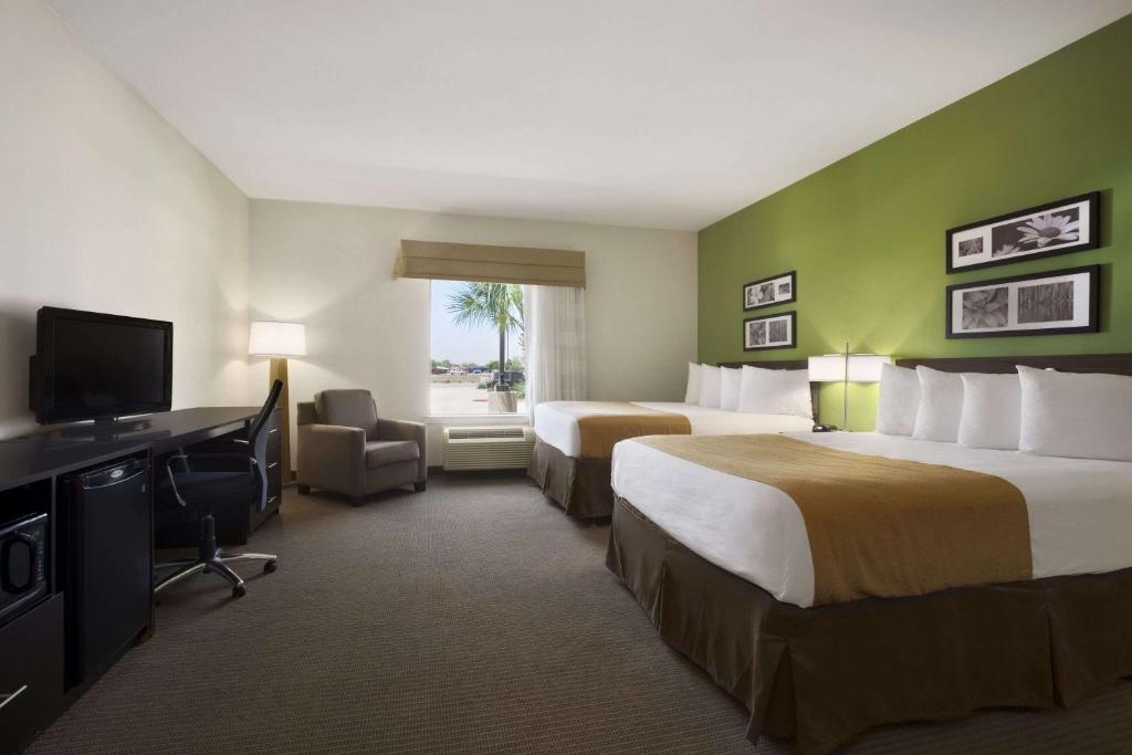 a hotel room with two beds and a flat screen tv at PetroStay Inn & Suites Cotulla in Cotulla