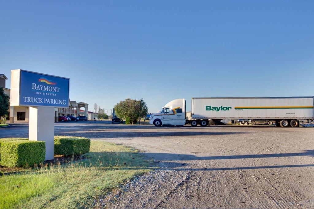 een vrachtwagen die langs een weg naast een bord rijdt bij Baymont by Wyndham Terrell in Terrell