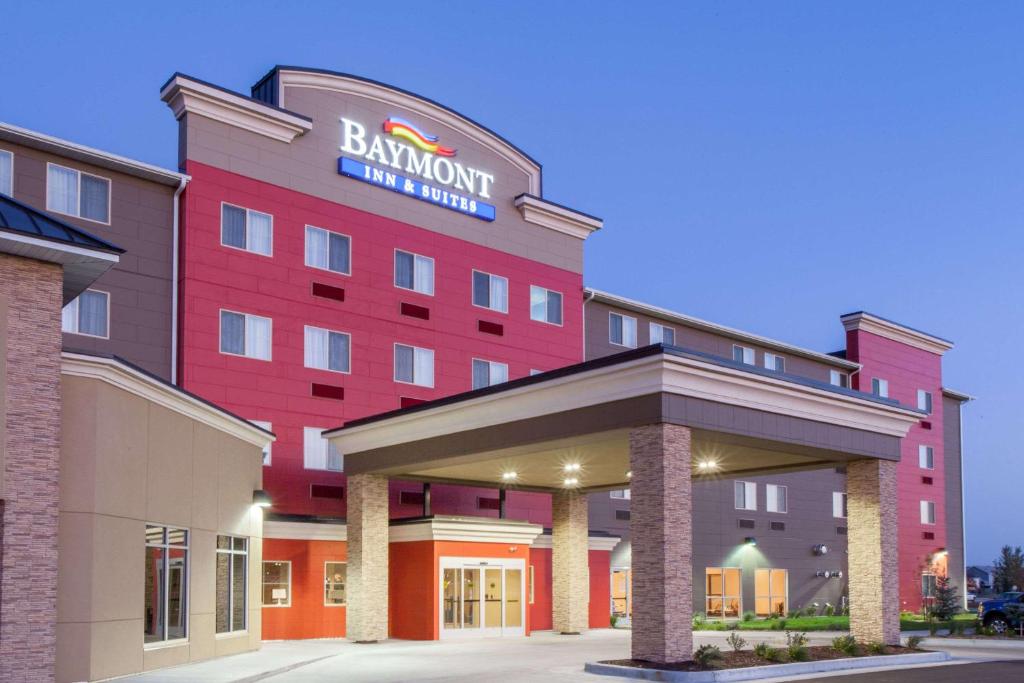 un hotel con un edificio rojo con un cartel en él en Baymont by Wyndham Grand Forks, en Grand Forks