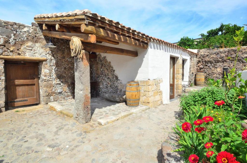 a stone building with a wooden door and flowers at S'Ommu Ezza in Narbolia