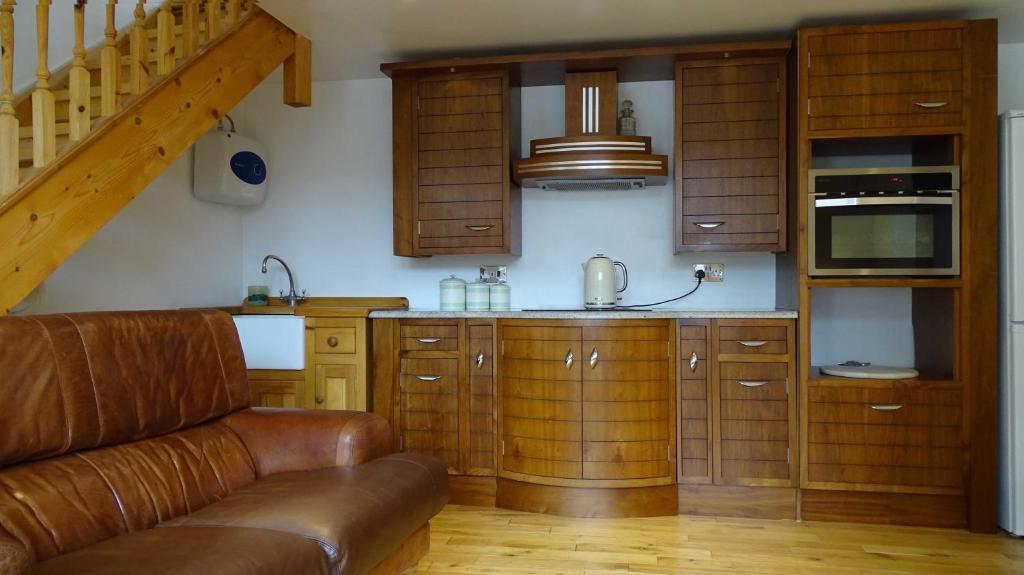 a kitchen with wooden cabinets and a brown leather couch at Batley House in Westgate-on-Sea