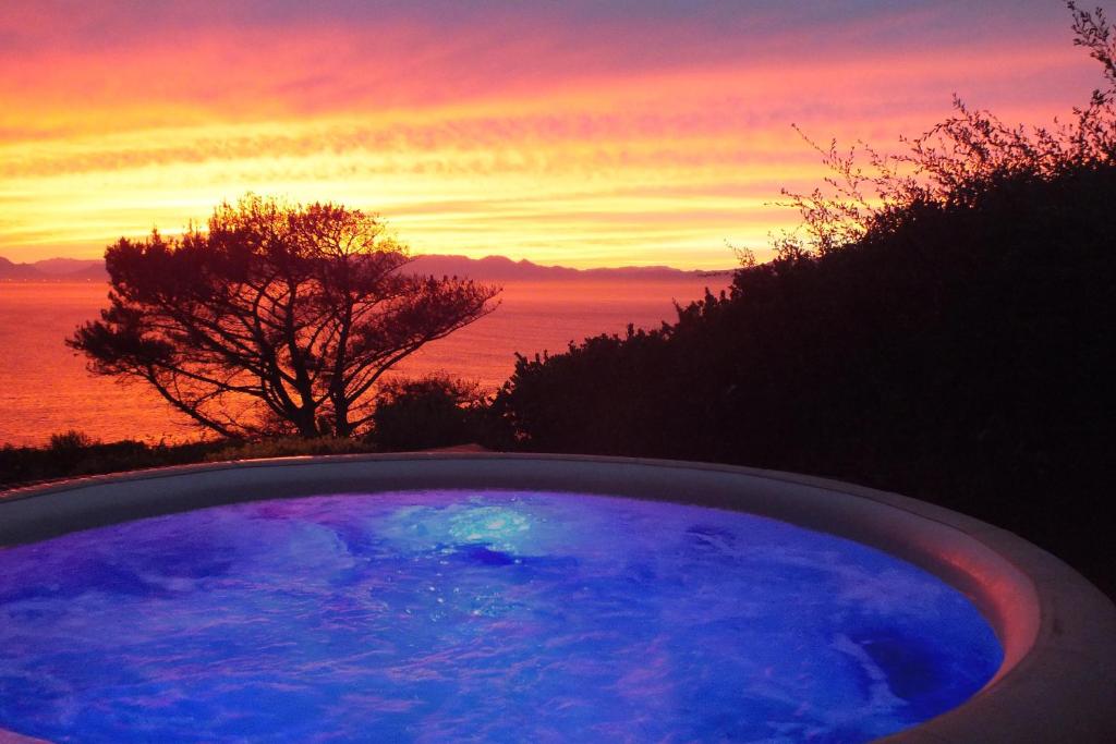 a hot tub with a sunset in the background at Penguinden - load-shedding free in Simonʼs Town
