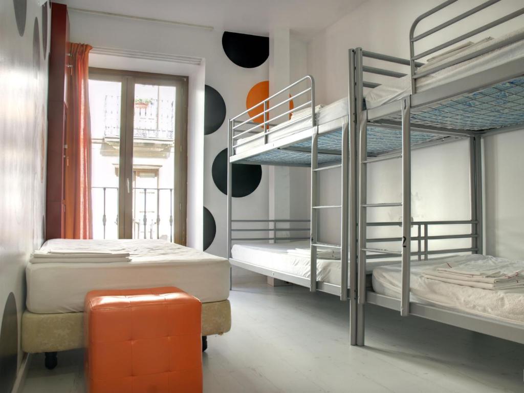 a room with two bunk beds and an orange stool at Albergue Revolutum Hostel in Salamanca