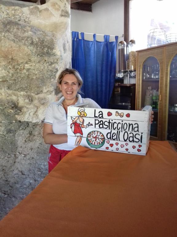 a woman holding a sign in front of a table at L'Oasi Villaggio Albergo in Favignana