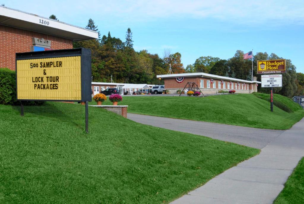 a yellow sign in the grass next to a building at Budget Host Crestview Inn in Sault Ste. Marie