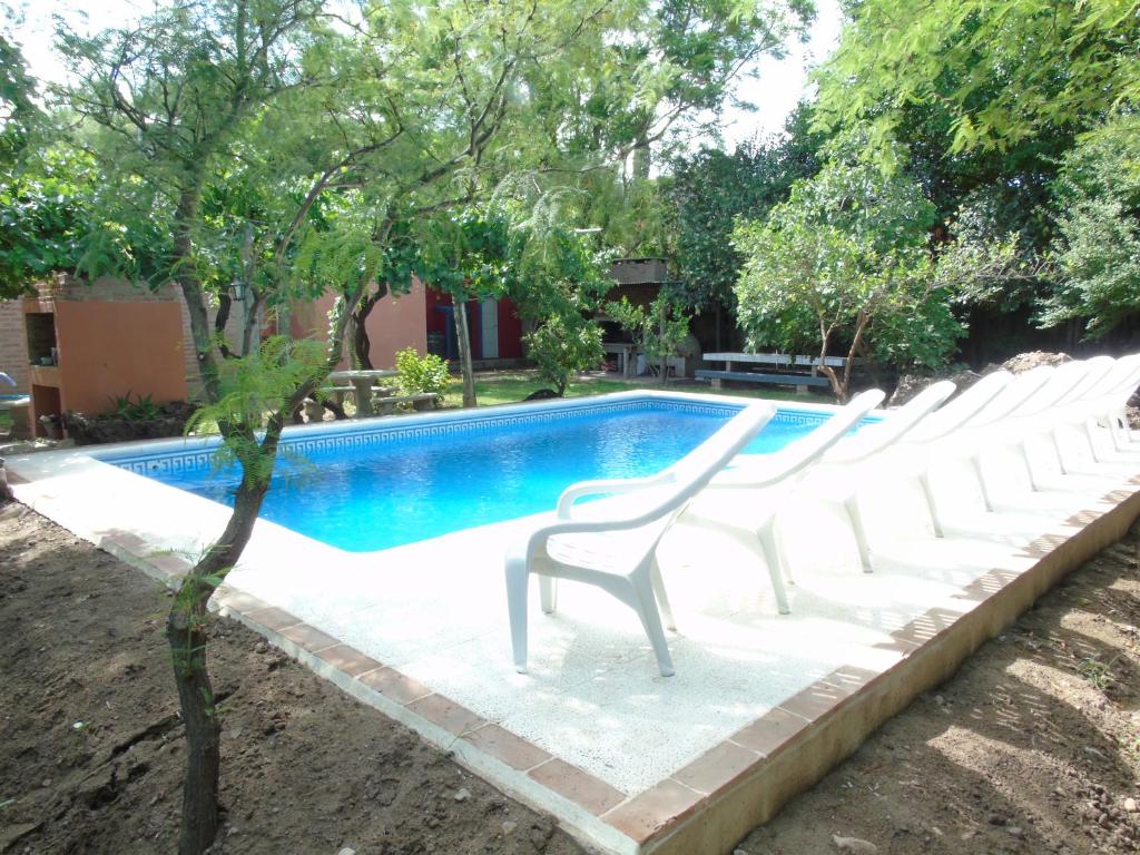 uma fila de cadeiras brancas sentadas ao lado de uma piscina em Apart-Cabañas De La Plaza em San Marcos Sierras