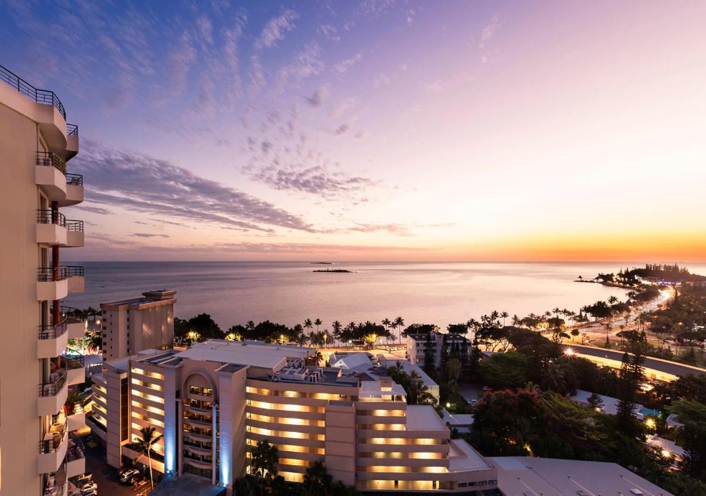 Ramada Hotel & Suites by Wyndham Noumea في نومْيا: اطلالة على الشاطئ والمباني ليلا