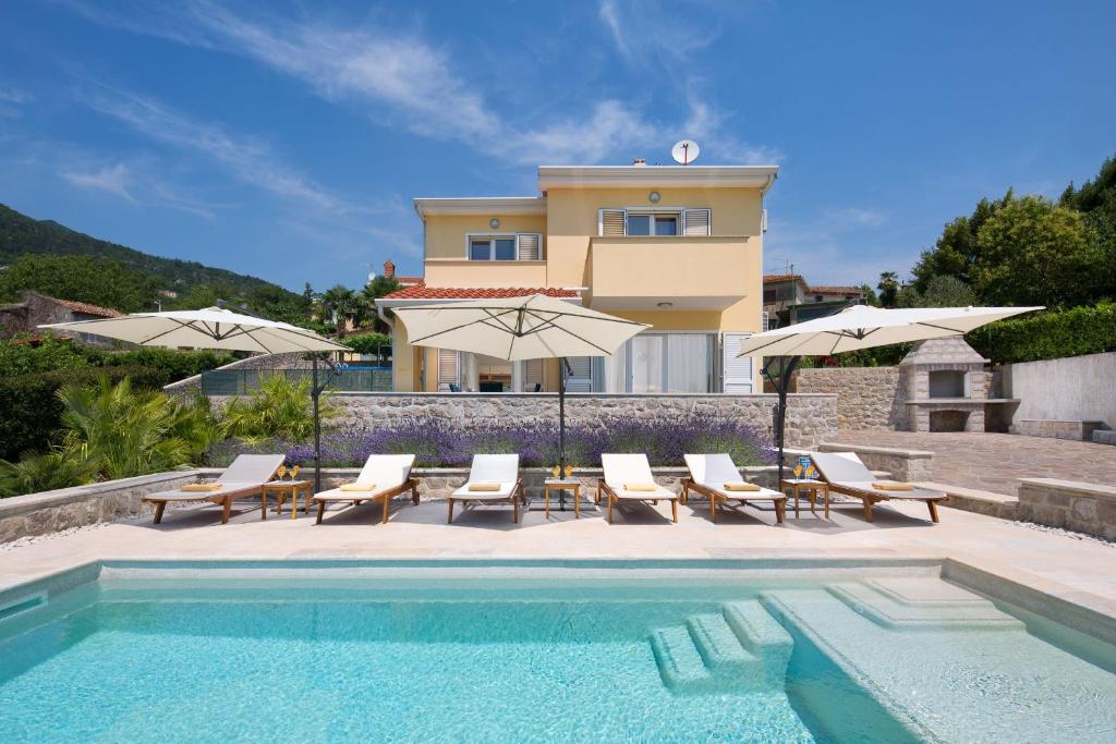a swimming pool with chairs and umbrellas next to a house at Villa Silvija in Poljane