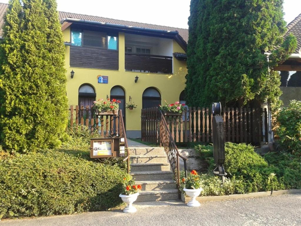 a yellow house with stairs and flowers in front of it at Fehér Ló Fogadó in Bük