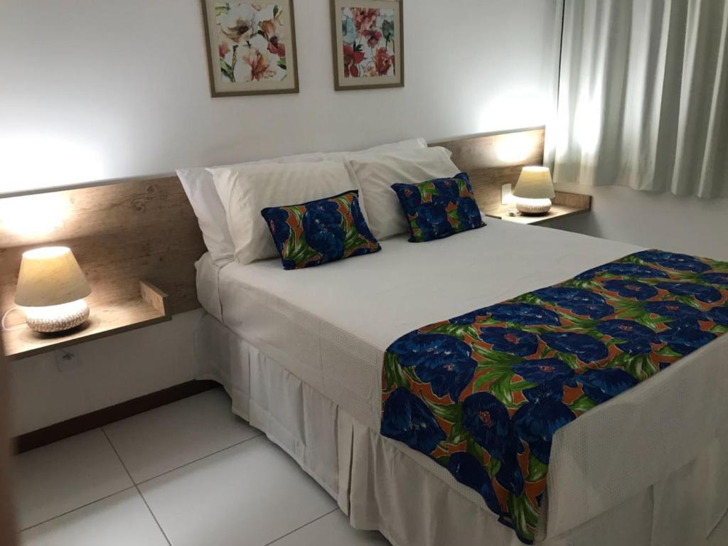 a bed in a room with two lamps on tables at Residence Iloa Resort in Barra de São Miguel