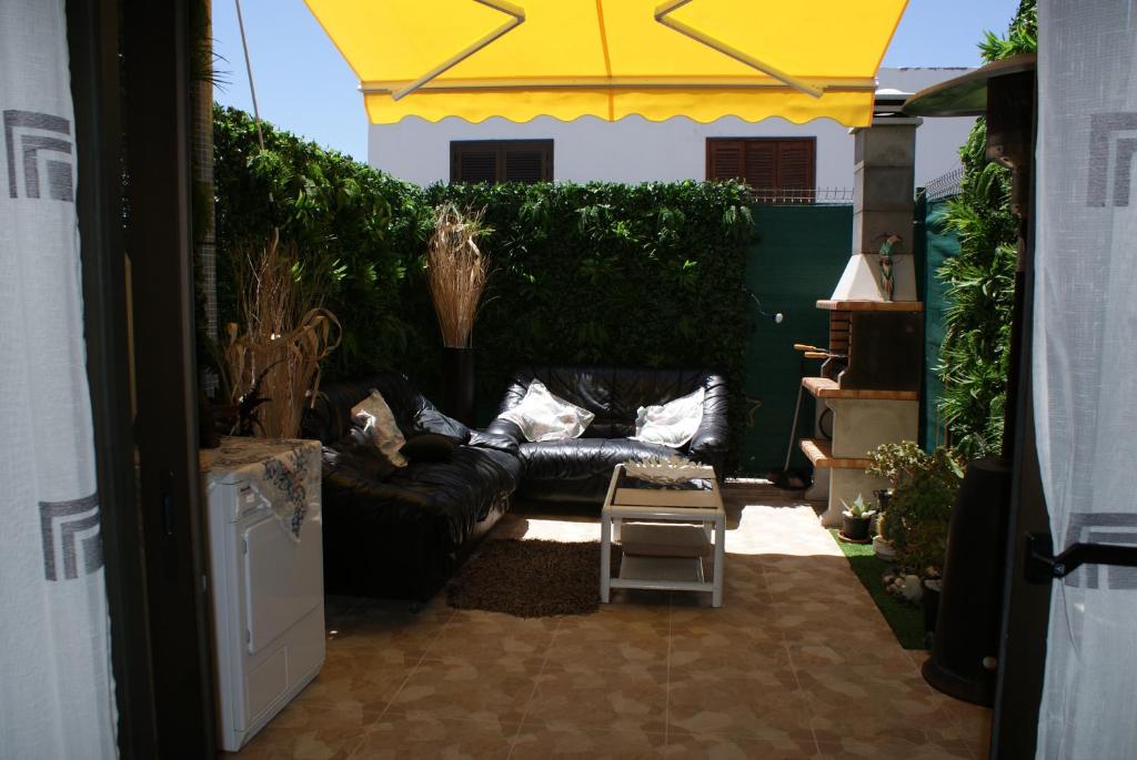 a patio with a black couch and a yellow umbrella at Room Complex Bungamar in Playa de las Americas