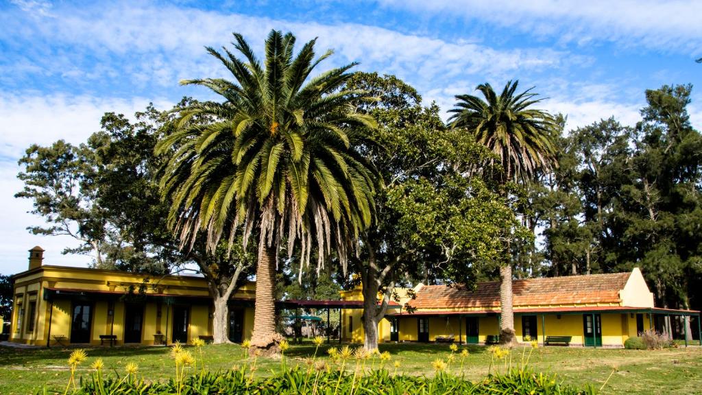 una casa con due palme di fronte di Estancia La Margarita a Chascomús