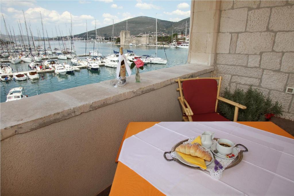 a table with a plate of food on a balcony with a harbor at Villa Moretti in Trogir