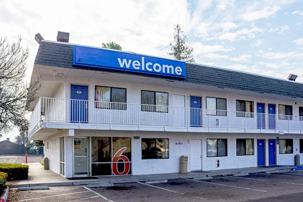 un panneau de bienvenue sur le côté d'un bâtiment dans l'établissement Motel 6-Porterville, CA, à Porterville