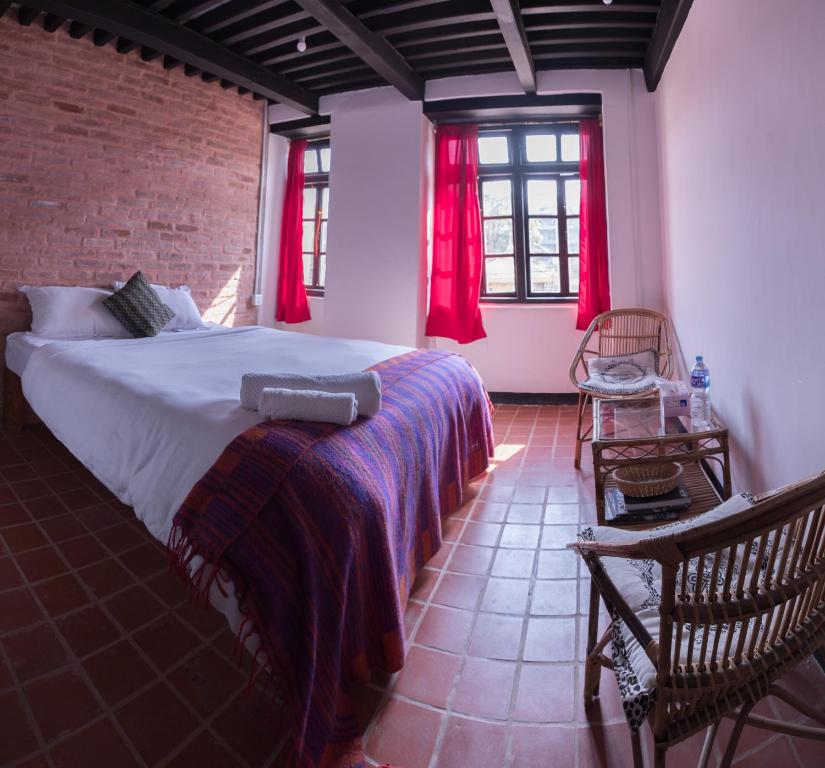 a bedroom with a large bed with red curtains at Lumbini Heritage Home in Pātan