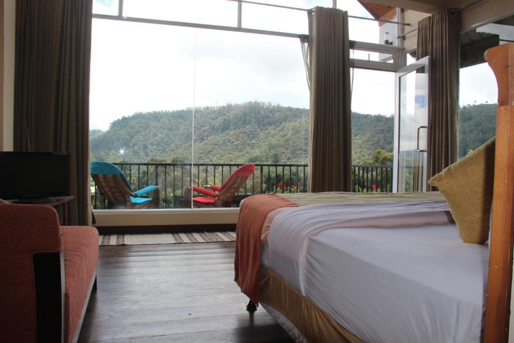 - une chambre avec un lit et un balcon avec vue dans l'établissement Pigeons Nest, à Nuwara Eliya