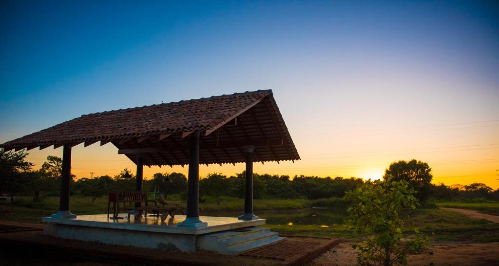 a pavilion with a table and chairs at sunset at Kumbukgaha Villa in Sigiriya