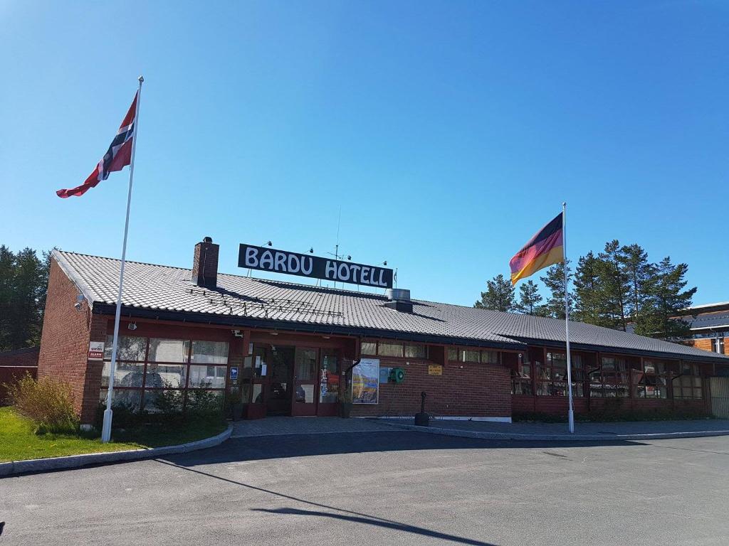 two flags are flying in front of a store at Bardu Hotell in Sætermoen