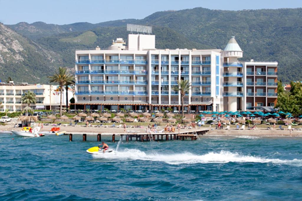 a person on a boat in the water in front of a hotel at Faustina Hotel & Spa in Güzelçamlı