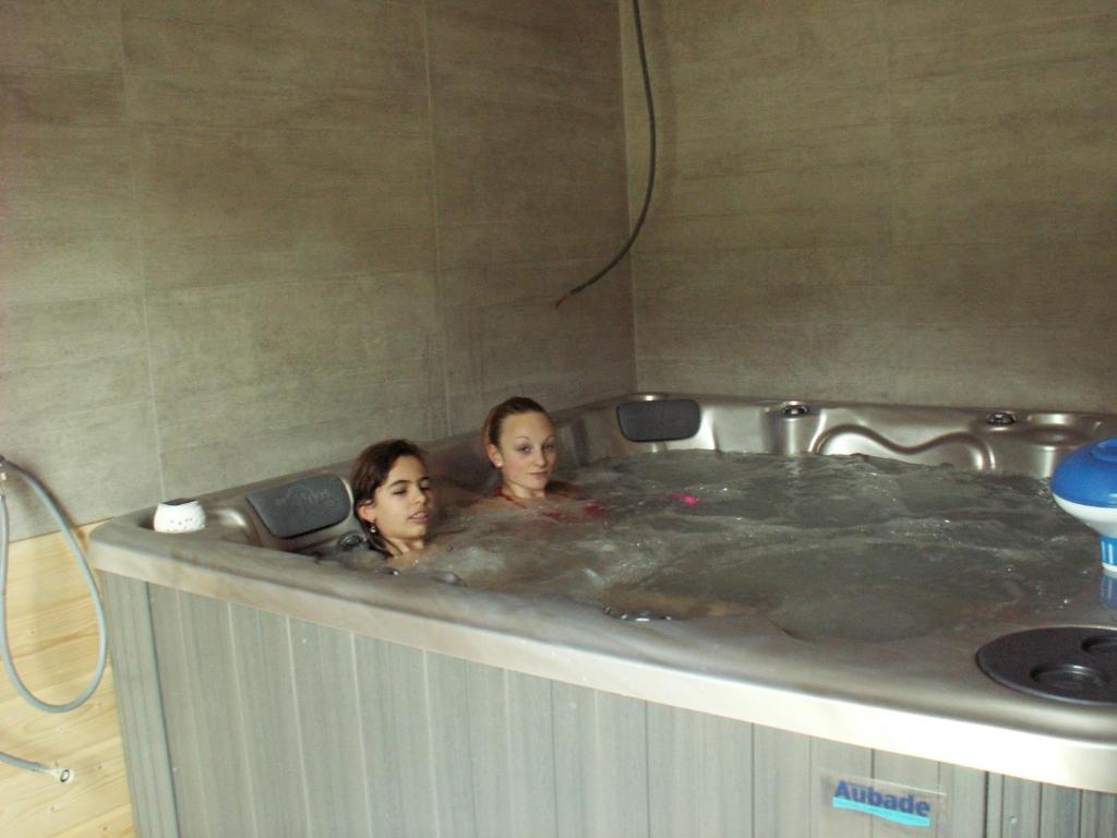 two women in a jacuzzi in a bathtub at chalet vosgien in Le Ménil