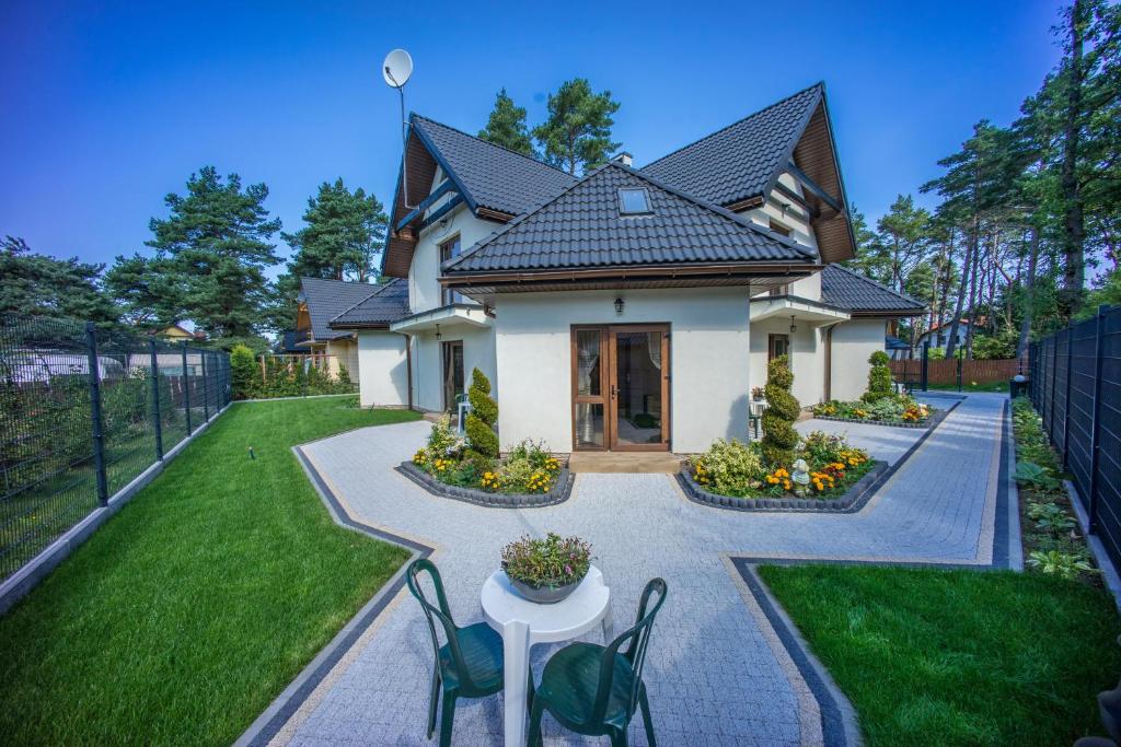 a house with a table and chairs in a yard at Willa Pogodna in Jarosławiec