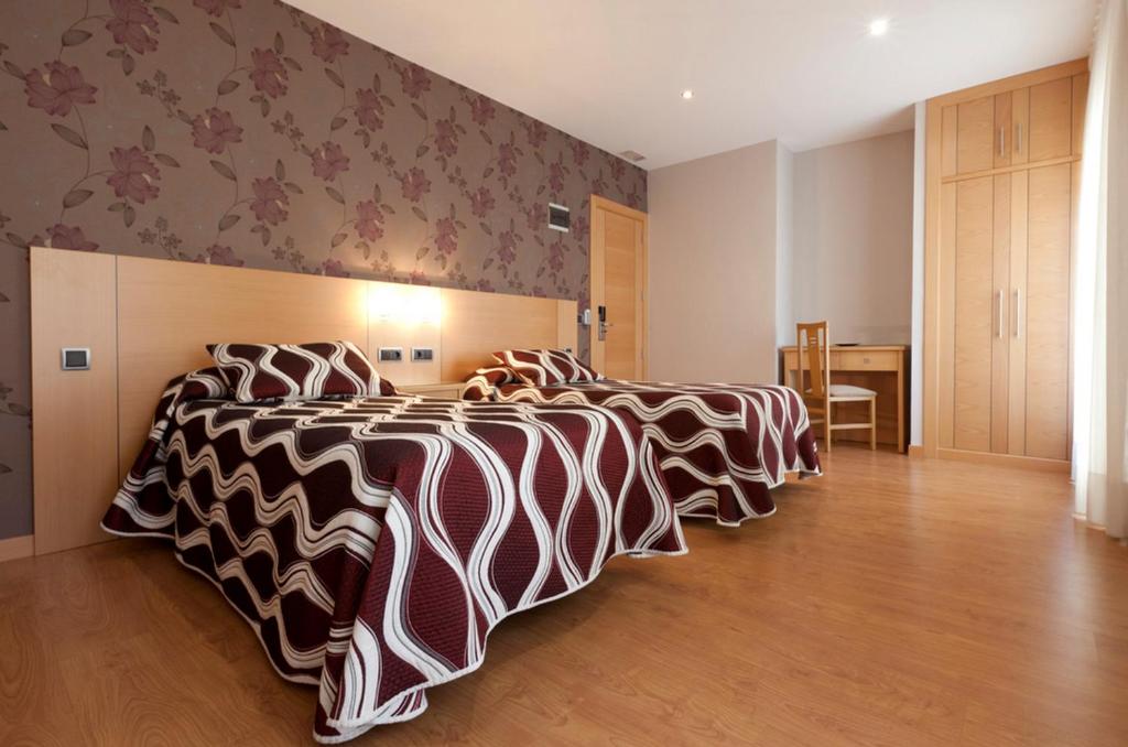 Hostal Jemasaca-Palma61 في مدريد: غرفة نوم بثلاث اسرة عليها شرشف مقلم